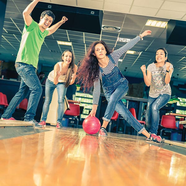 Youth friends bowling down lane